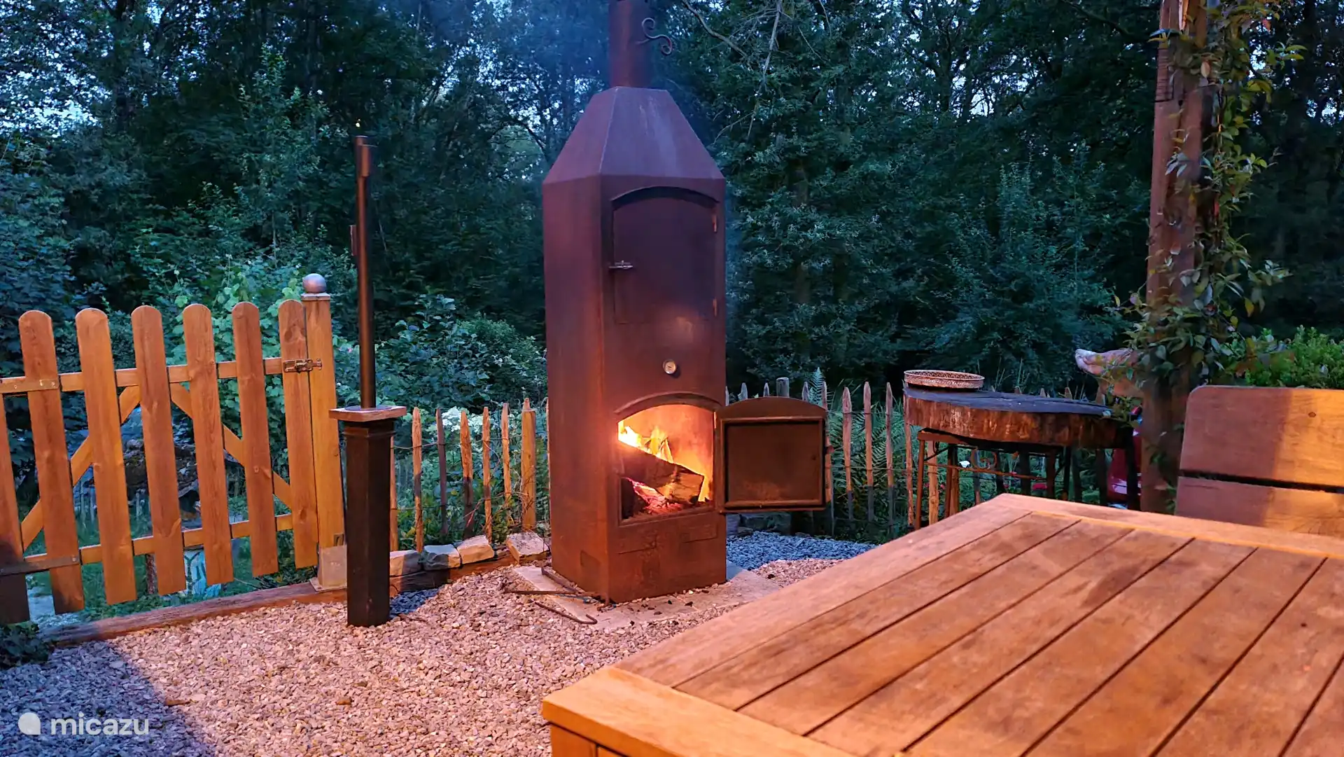 Setzen Sie sich draußen auf die Terrasse am gemütlichen Kaminfeuer 