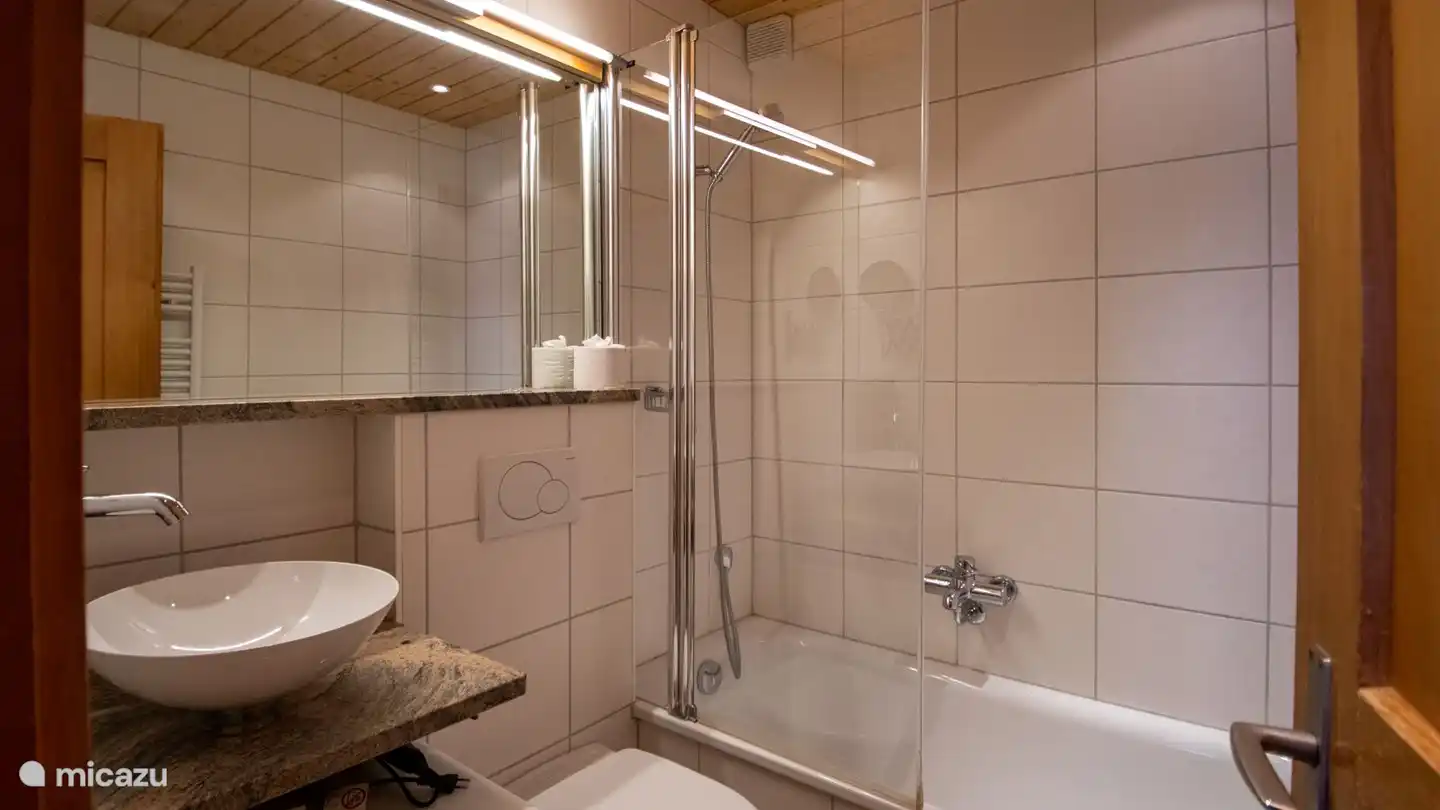 1 luxuriöses Badezimmer mit Waschbecken, Toilette und Badewanne/Dusche. 