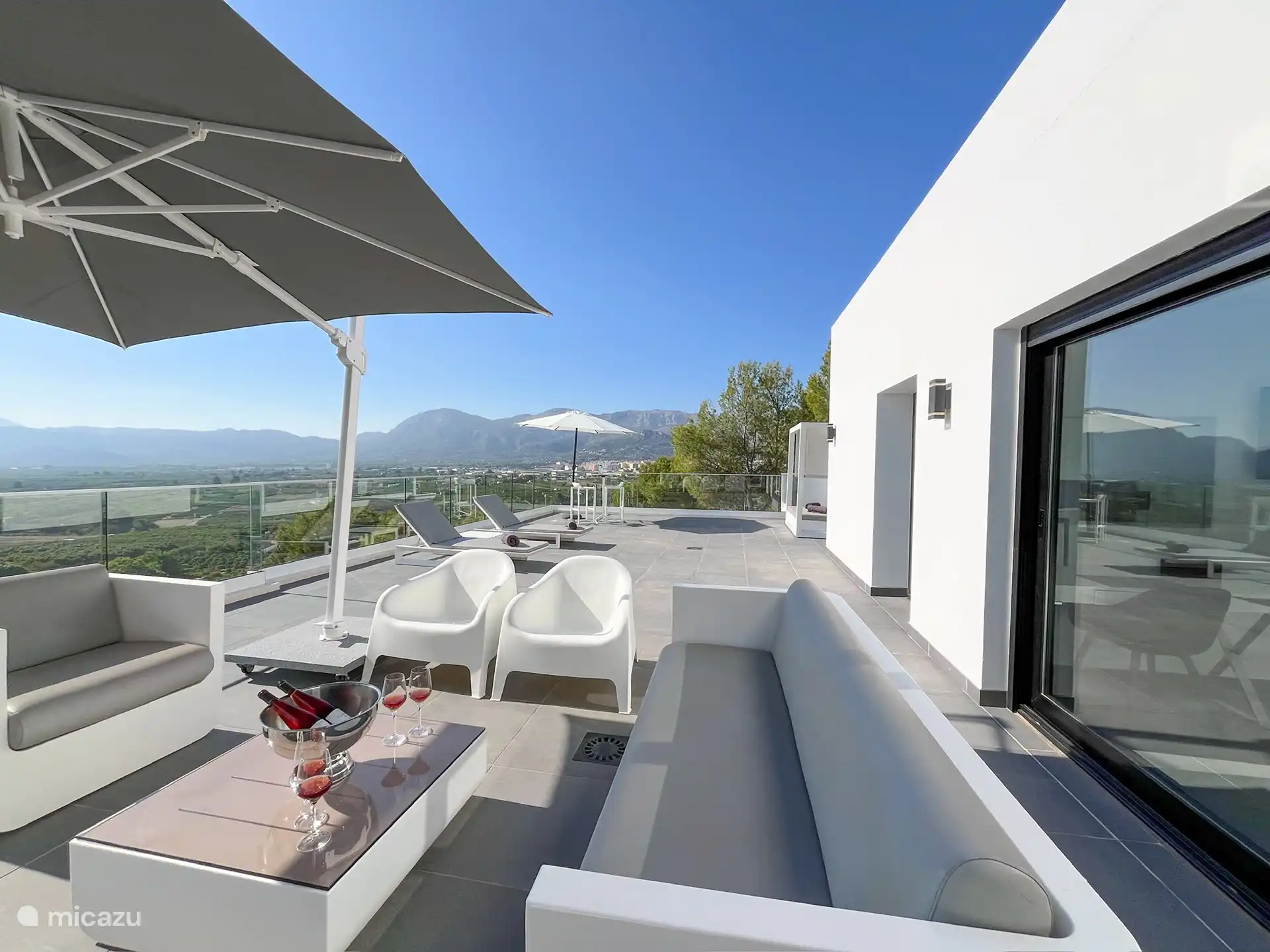 Dakterras met loungeset, ligbedden en parasols