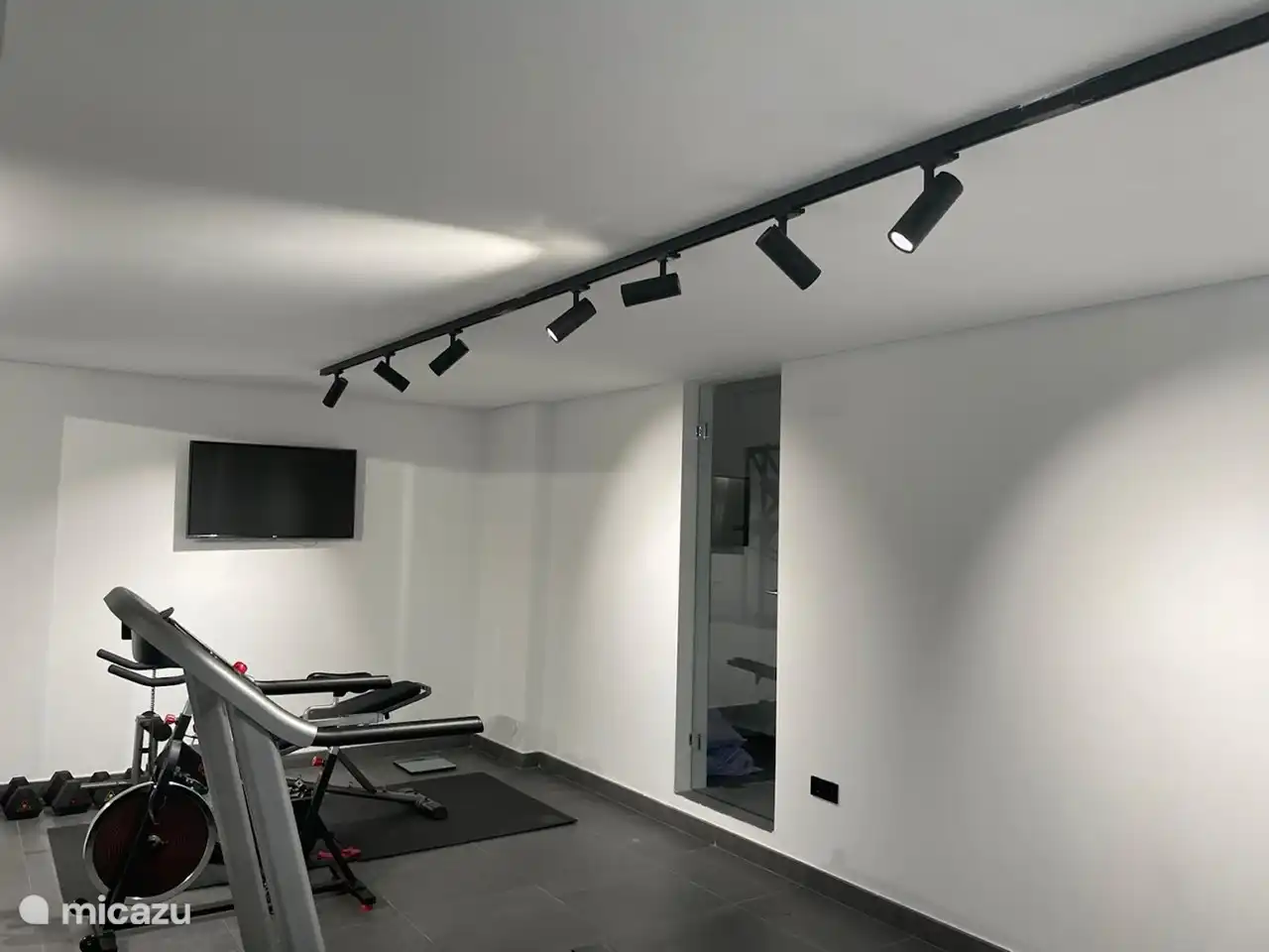 De gym op de begane grond voorzien van yoga mat, roeiapparaat, loopband, hometrainer en beenspieren bank. Speel je favoriete workout op de TV af en leef je uit! 