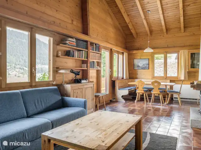 Trimka | Suisse, Valais, Fiesch - appartement salon spacieux avec cheminée où l'on regarde les poutres du toit.