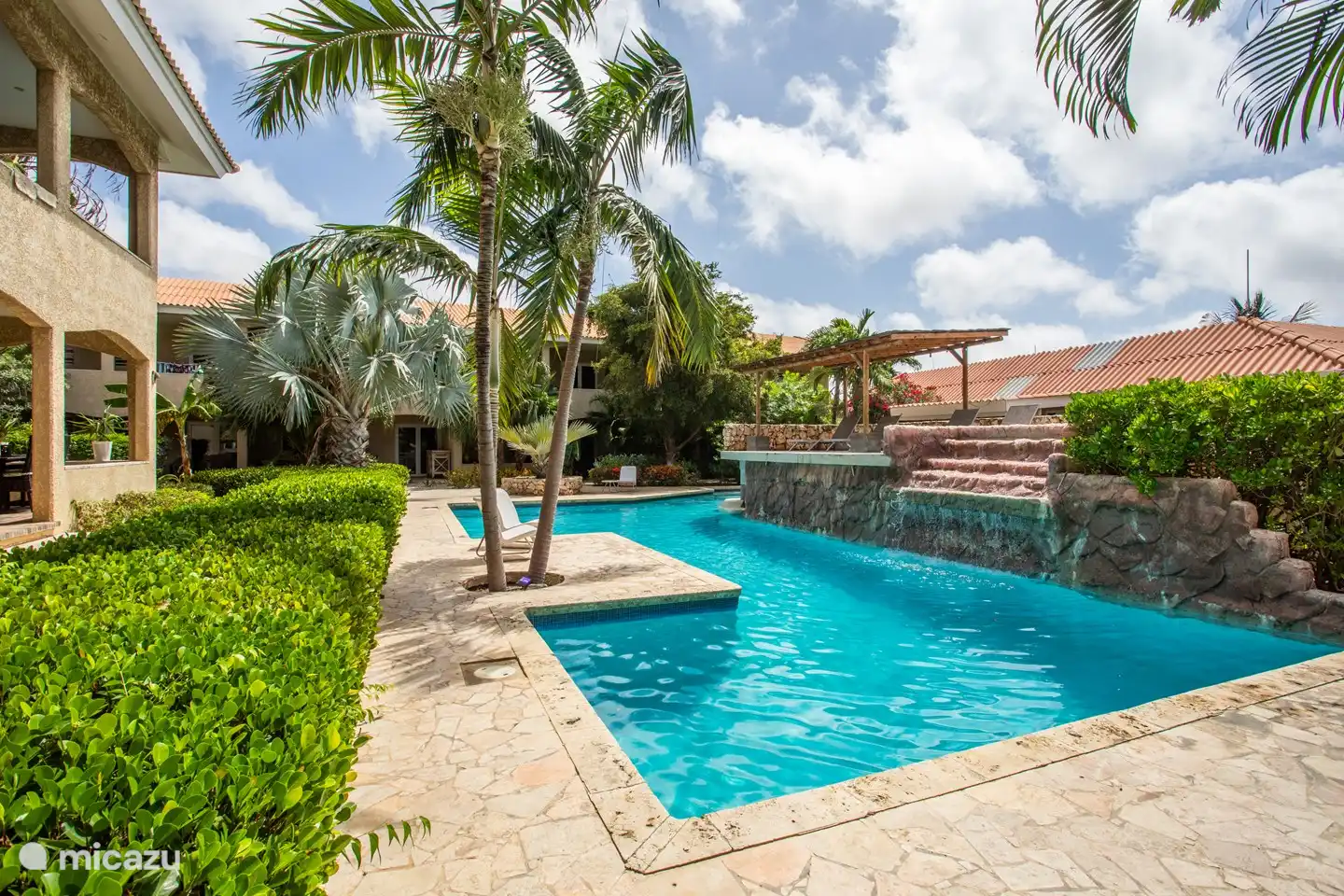 Piscine spacieuse et belle avec cascade, transats confortables et une terrasse, parfaite pour se détendre et se rafraîchir.