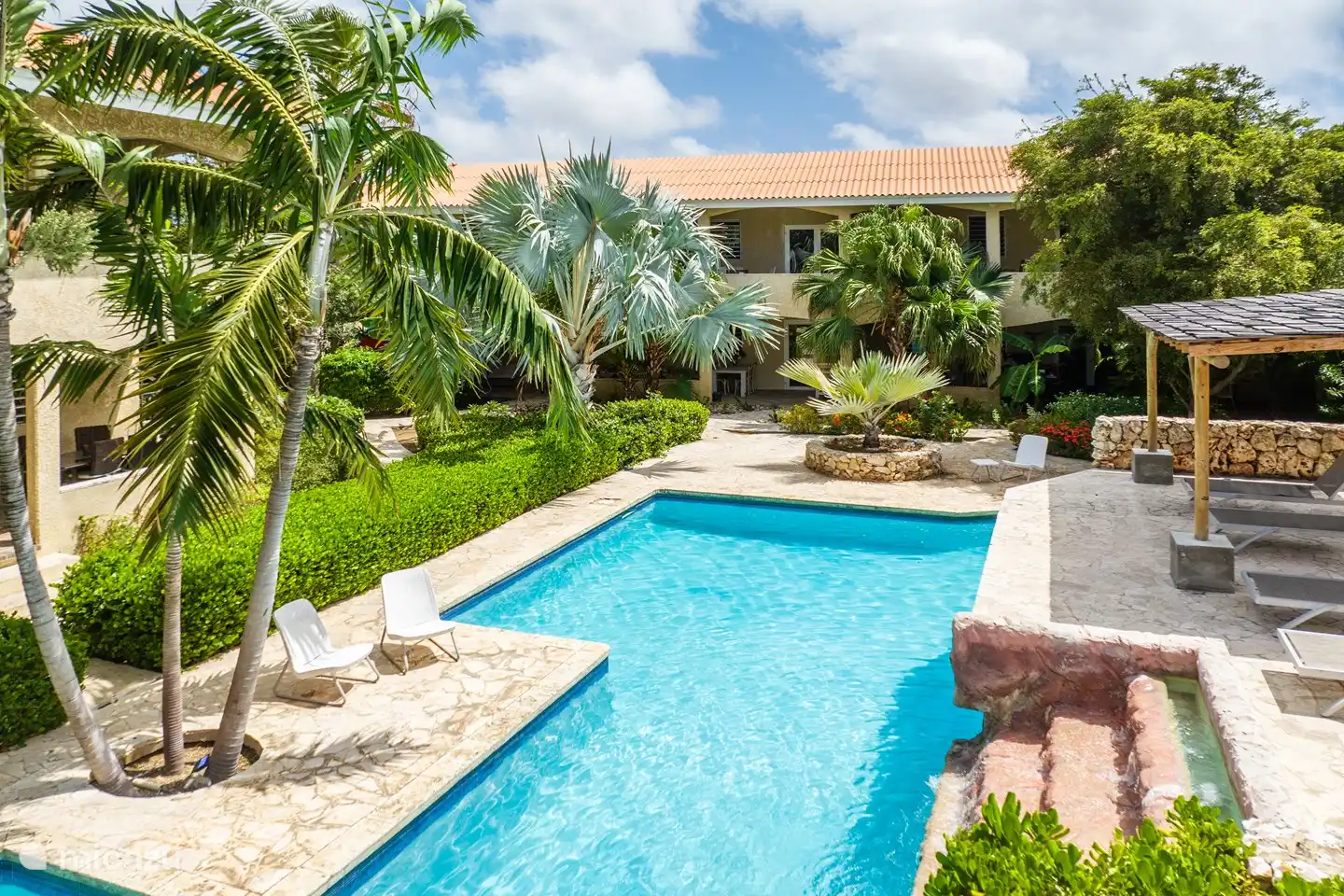 Piscine spacieuse et belle avec cascade, transats confortables et une terrasse, parfaite pour se détendre et se rafraîchir.