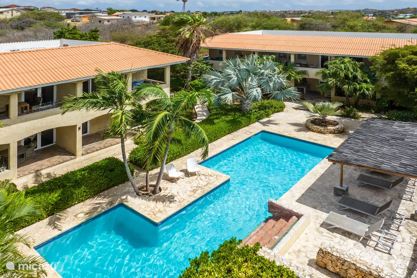 Piscine spacieuse et belle avec cascade, transats confortables et une terrasse, parfaite pour se détendre et se rafraîchir.