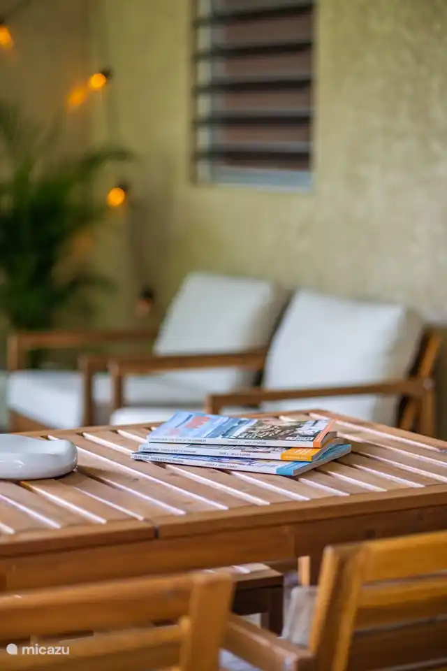 Porche spacieux au rez-de-chaussée avec accès direct à la piscine, abrité par des plantes tropicales et des arbres. Comprend un coin salon confortable, une table à manger et un ventilateur de plafond pour plus de confort