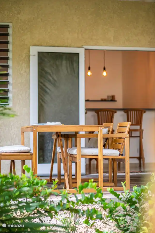 Porche spacieux au rez-de-chaussée avec accès direct à la piscine, abrité par des plantes tropicales et des arbres. Comprend un coin salon confortable, une table à manger et un ventilateur de plafond pour plus de confort