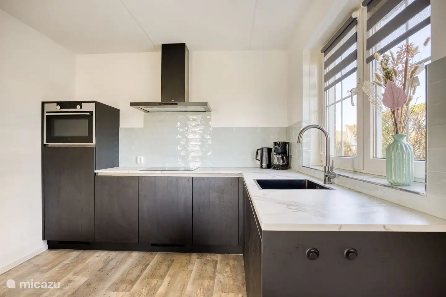 Luxusküche mit Geschirrspüler, Induktionskochfeld, großem Kühlschrank und Kombimikrowelle. Kücheninventar ist vorhanden.