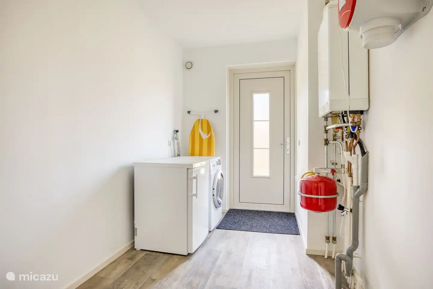 Waschküche mit Waschmaschine/Trockner-Kombination und separatem Gefrierschrank.