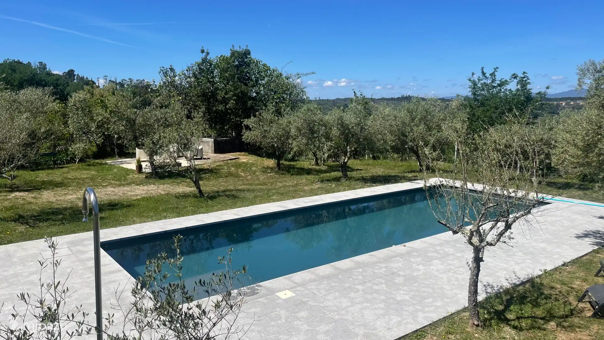 La piscine est située sur une terrasse plus basse que la maison, entre les oliviers, avec une terrasse supplémentaire avec un espace salon