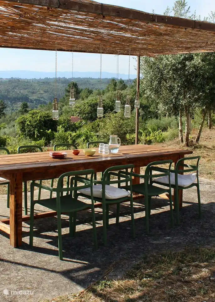 Unter dem Vordach mit Weidenmatten können Sie den langen Tisch aufstellen und inmitten der Natur mit Blick auf die Berge essen. 