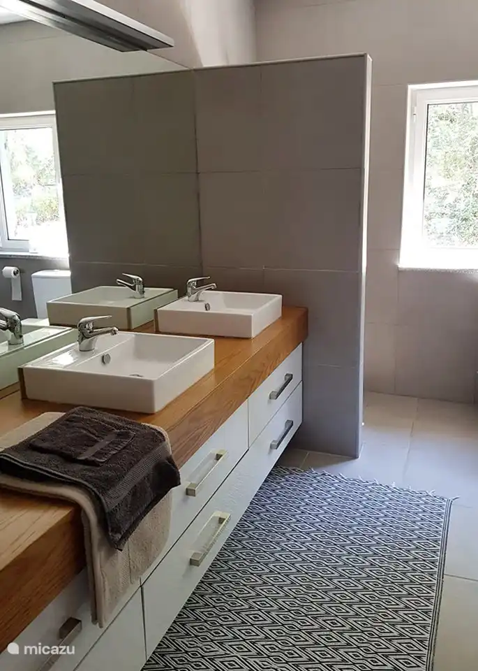 Das große Badezimmer mit Dusche hinter der Wand und schönem Licht durch das große Fenster.