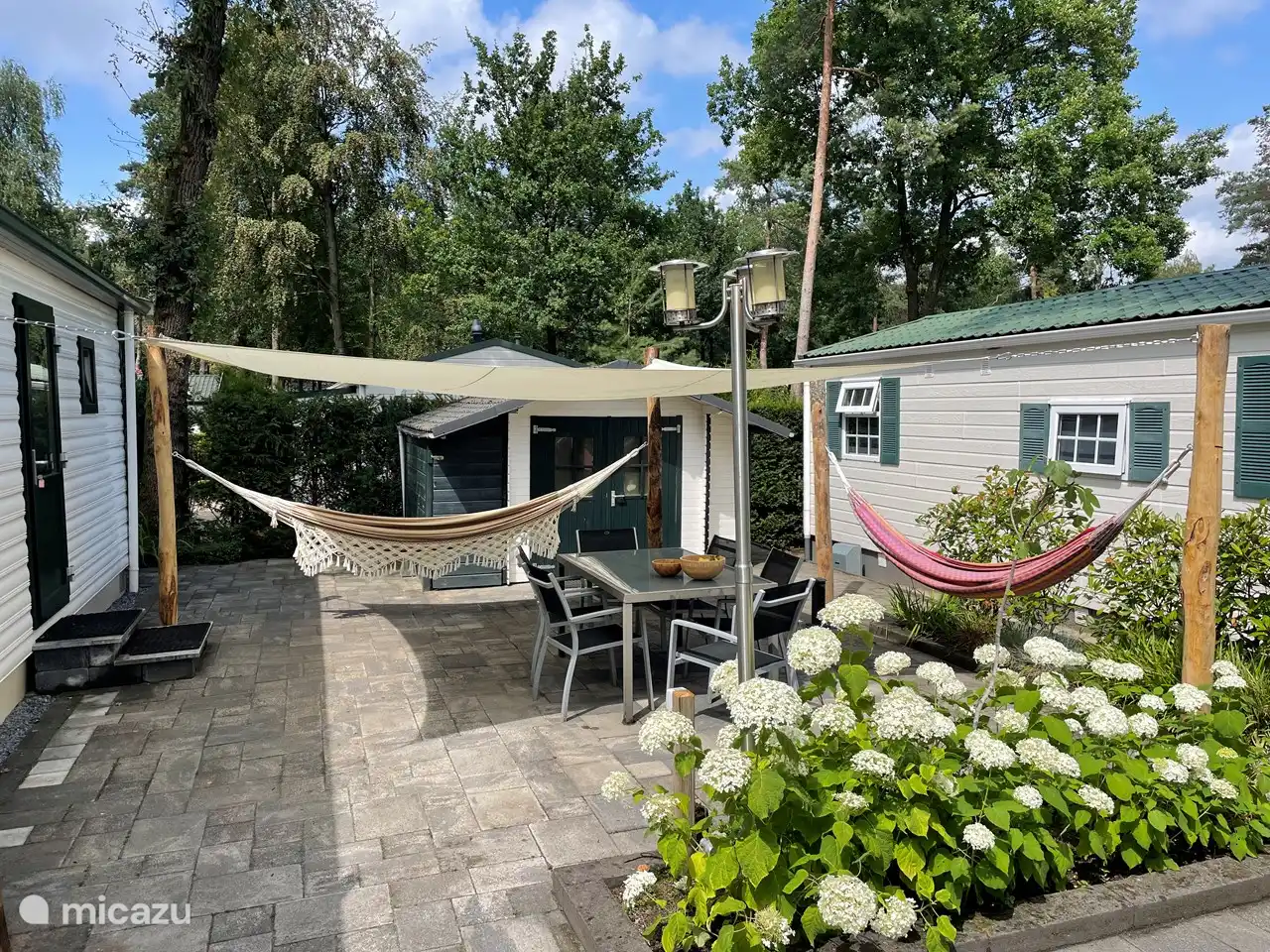 Heerlijke zonnige tuin met hangmatten en schaduwdoek.