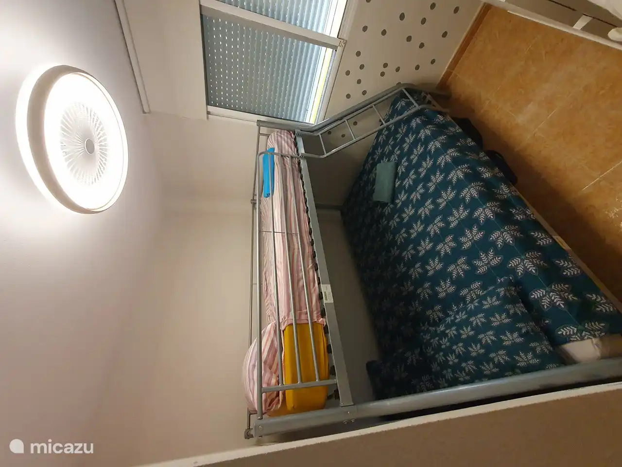 Slaapkamer voorzien van een stapelbed (bovenaan 90 cm breed op 2 m lang en onderaan 1.4 m breed op 2 m lang) met een plafondventilator op afstandsbediening.