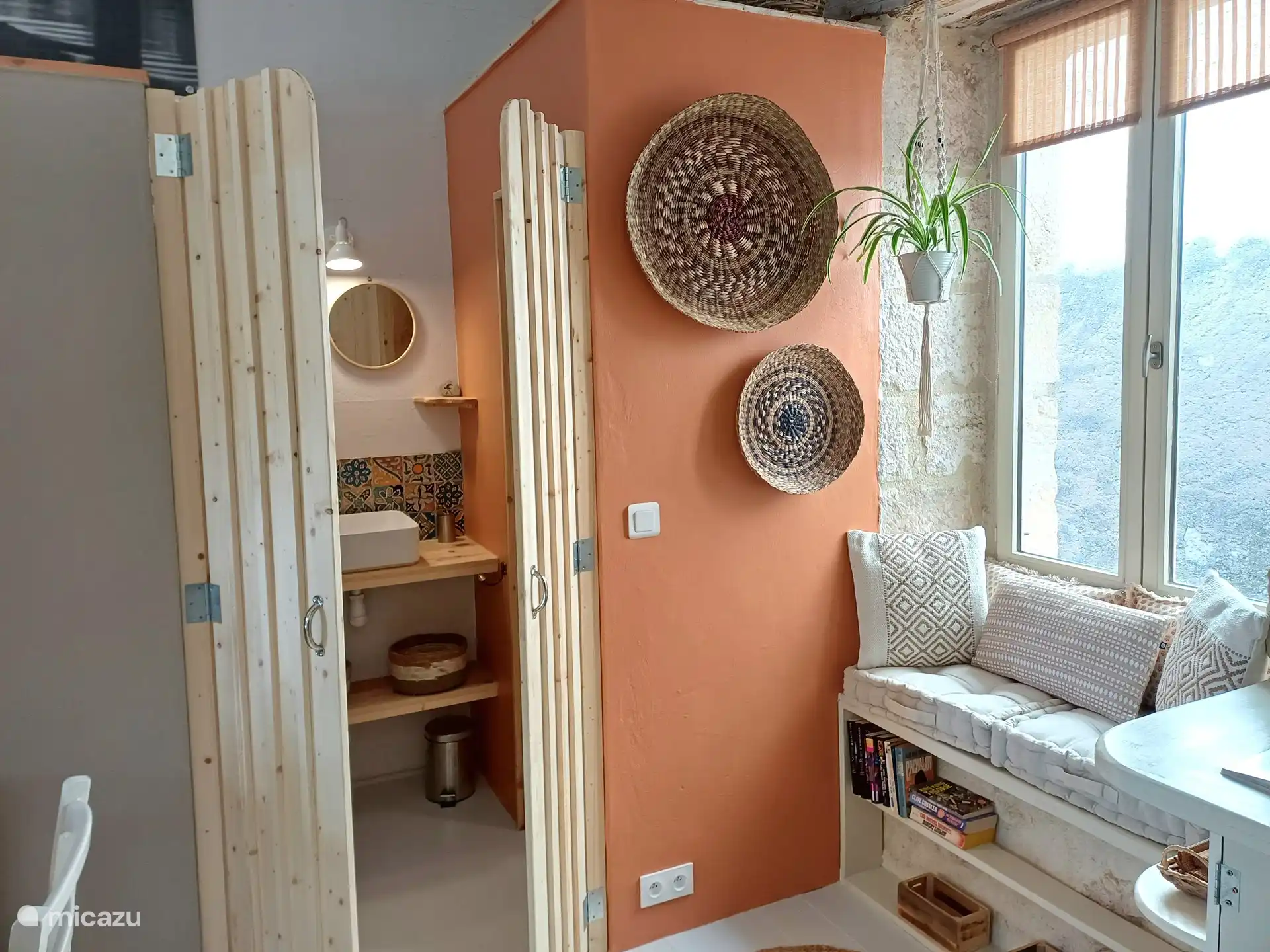 Sitzplatz vor dem Fenster und dem Zugang zu Dusche, Waschbecken und Toilette