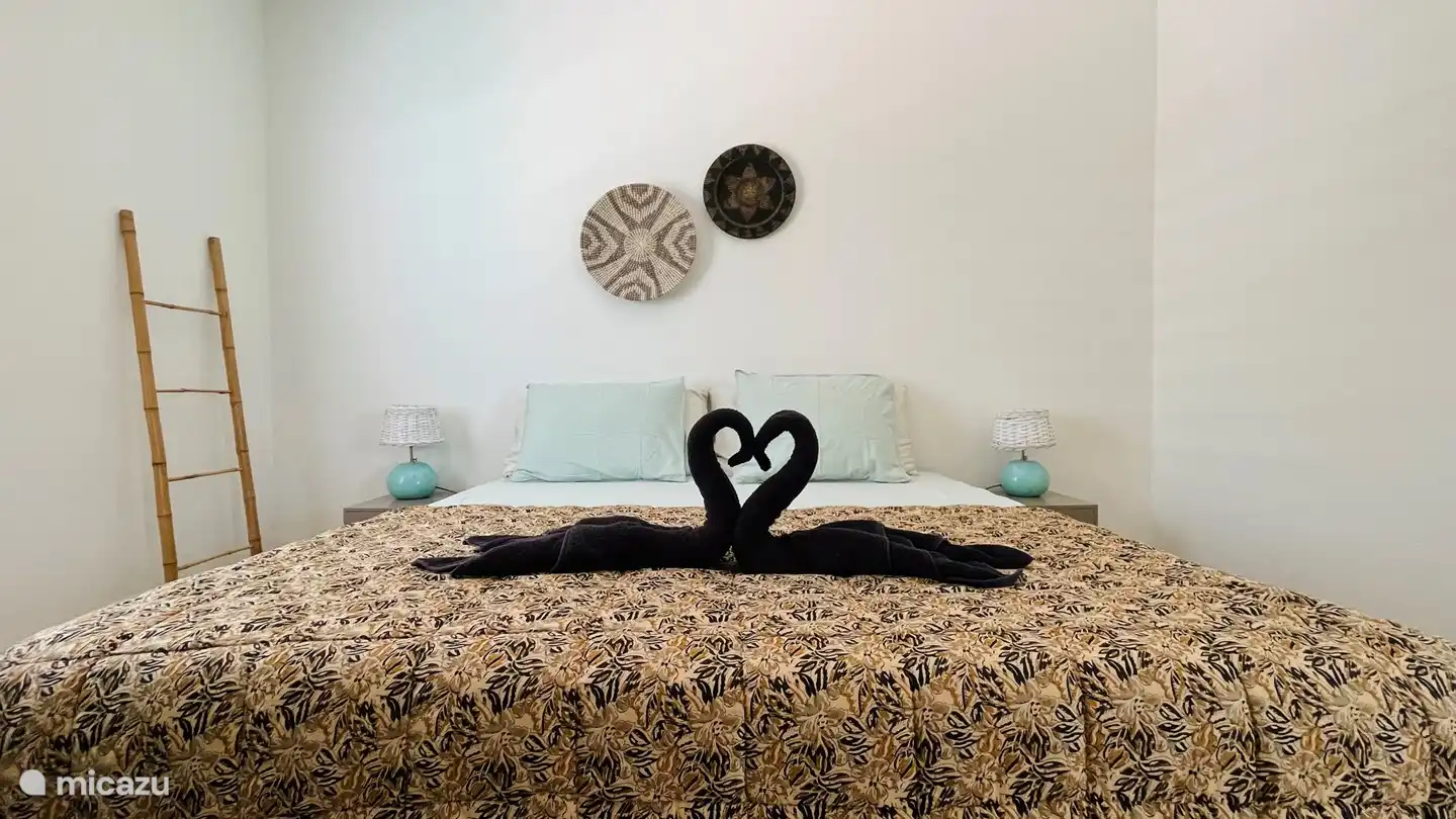 La chambre principale avec lit sommier hôtelier de 180 x 200 cm (2x 90x200 cm), 2 tables de chevet avec lampes, armoire à linge, miroir en pied, télévision, climatisation et salle de bain privée attenante.