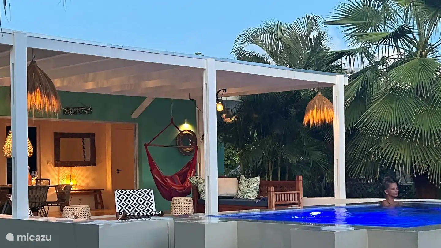 La véranda spacieuse et la belle piscine magnifiquement éclairée la nuit.