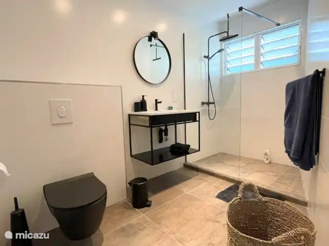 villa en Curazao, Curazao Centro, Piscadera – Invernadero Palmas Curacao El baño principal es accesible a través del dormitorio principal y ofrece un lavabo doble con espejo, ducha de lluvia y ducha de mano, inodoro, ventana de persiana de aluminio para una buena ventilación, secador de pelo y cesto de ropa.