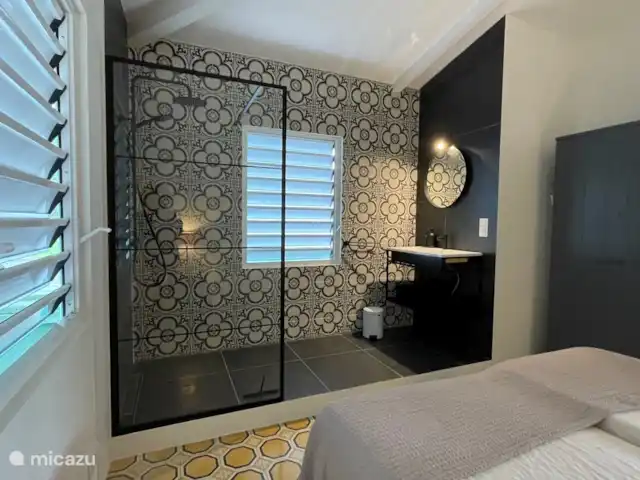 villa en Curazao, Curazao Centro, Piscadera – Invernadero Palmas Curacao El baño abierto del dormitorio 2 tiene ducha de lluvia, ducha de mano, lavabo con espejo, cesto de ropa y aire acondicionado.