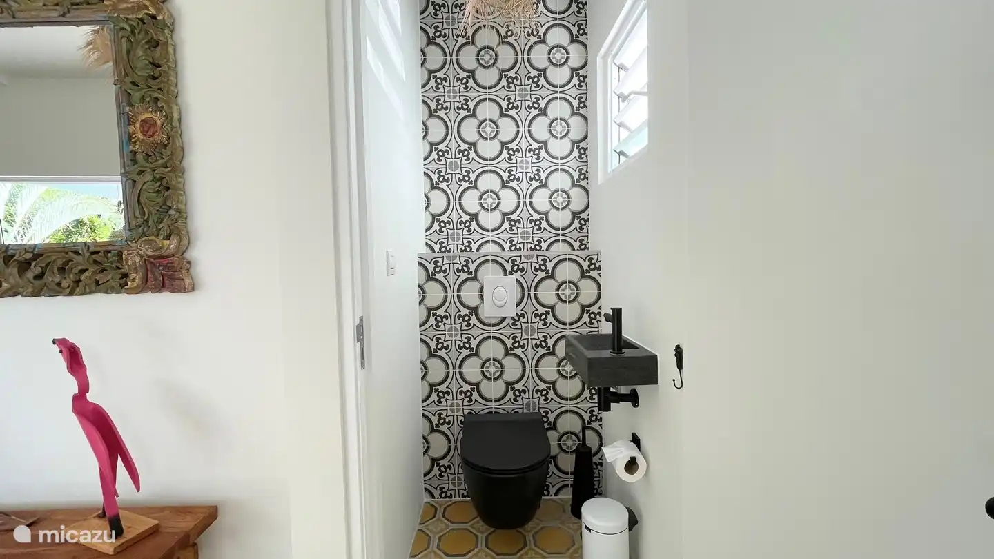 Les toilettes invités séparées avec lavabo et fenêtres à volets pour une bonne ventilation.