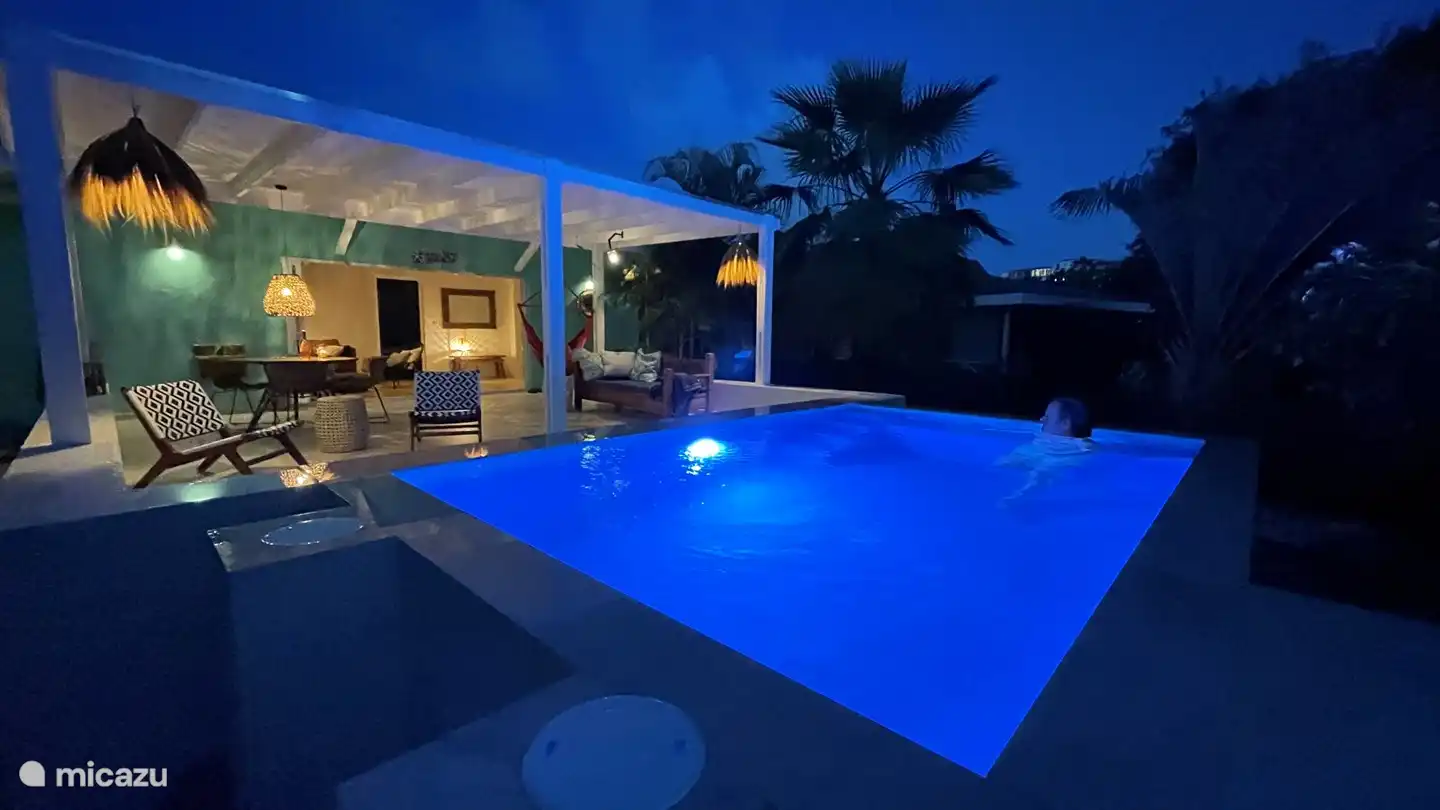 La véranda spacieuse et la belle piscine magnifiquement éclairée la nuit.