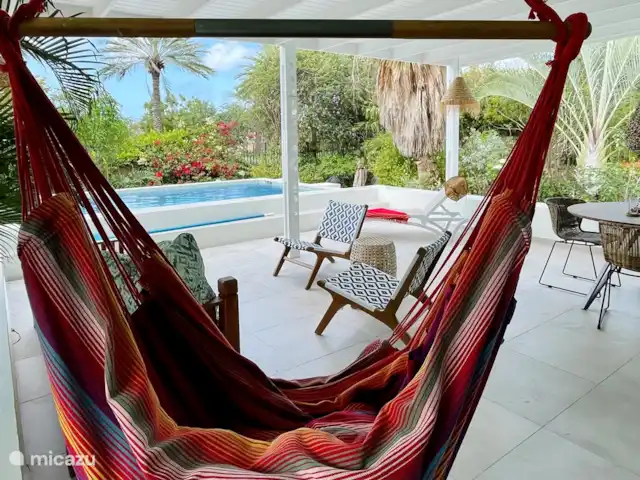 villa en Curazao, Curazao Centro, Piscadera – Invernadero Palmas Curacao La terraza ofrece varias zonas de estar, una silla colgante y una tumbona.