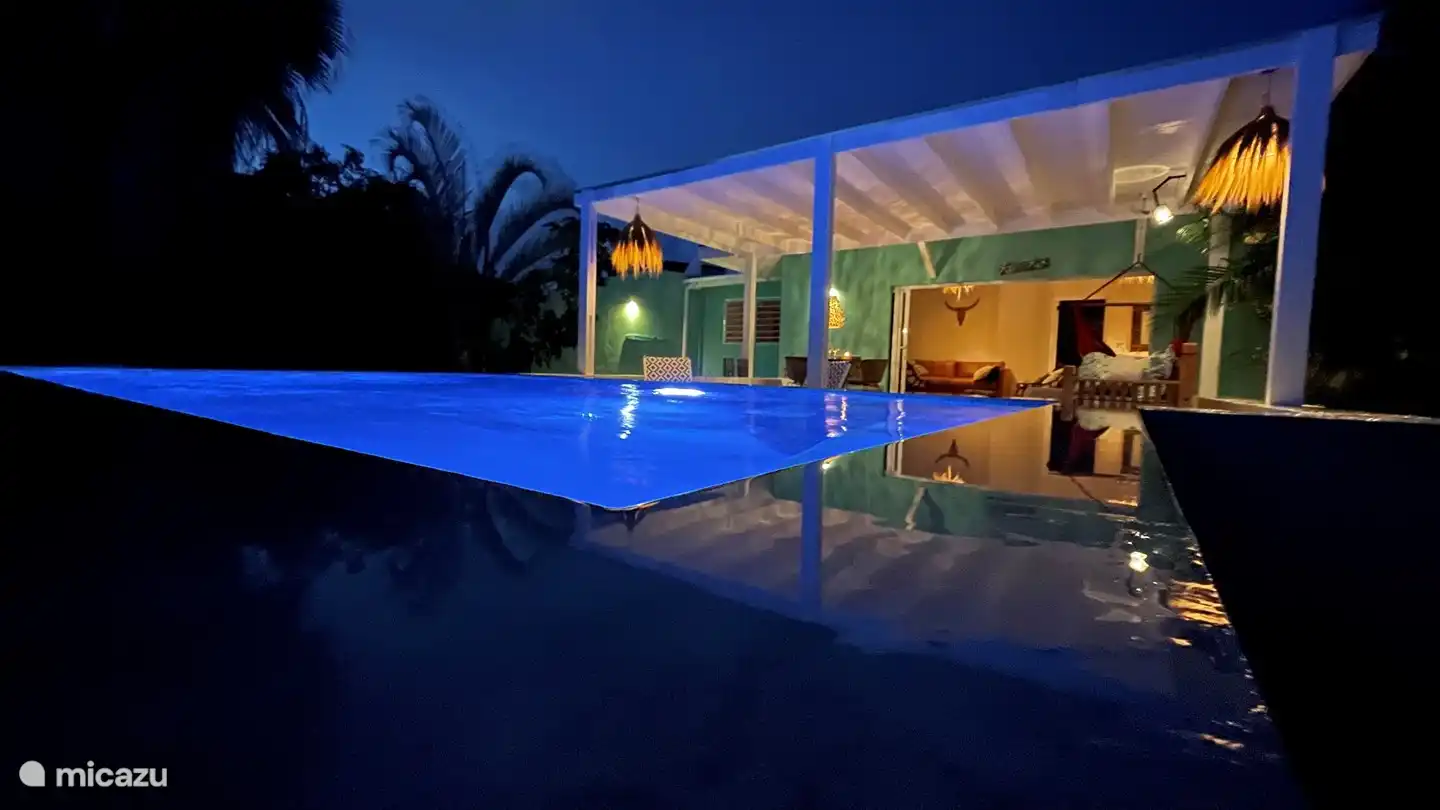 La véranda spacieuse et la belle piscine magnifiquement éclairée la nuit.