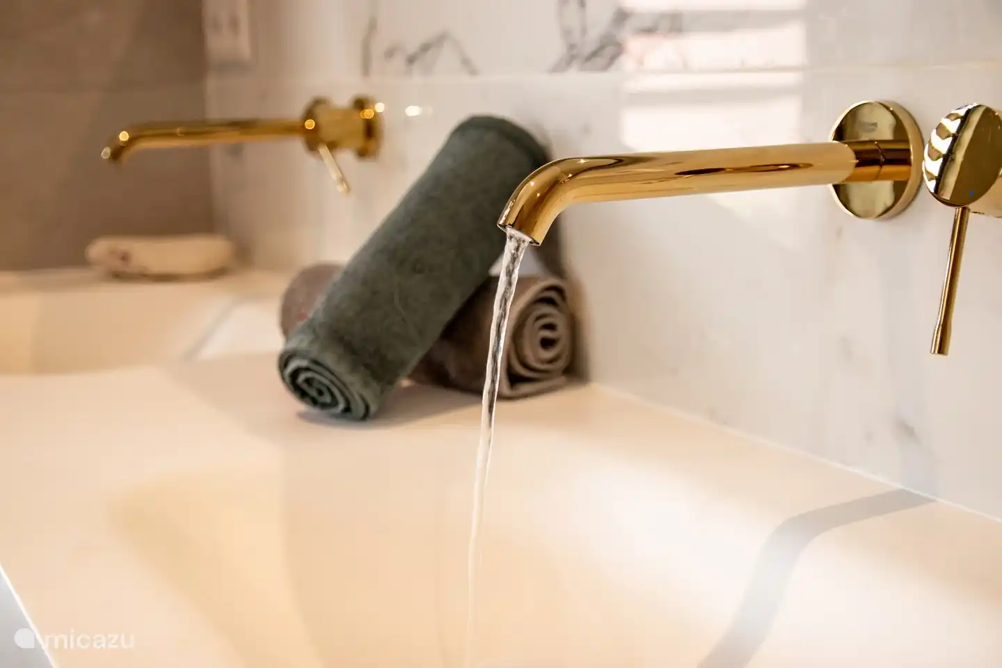 Die 2 Badezimmer im Erdgeschoss verfügen über weiße Marmorfliesen und goldene Einbauarmaturen