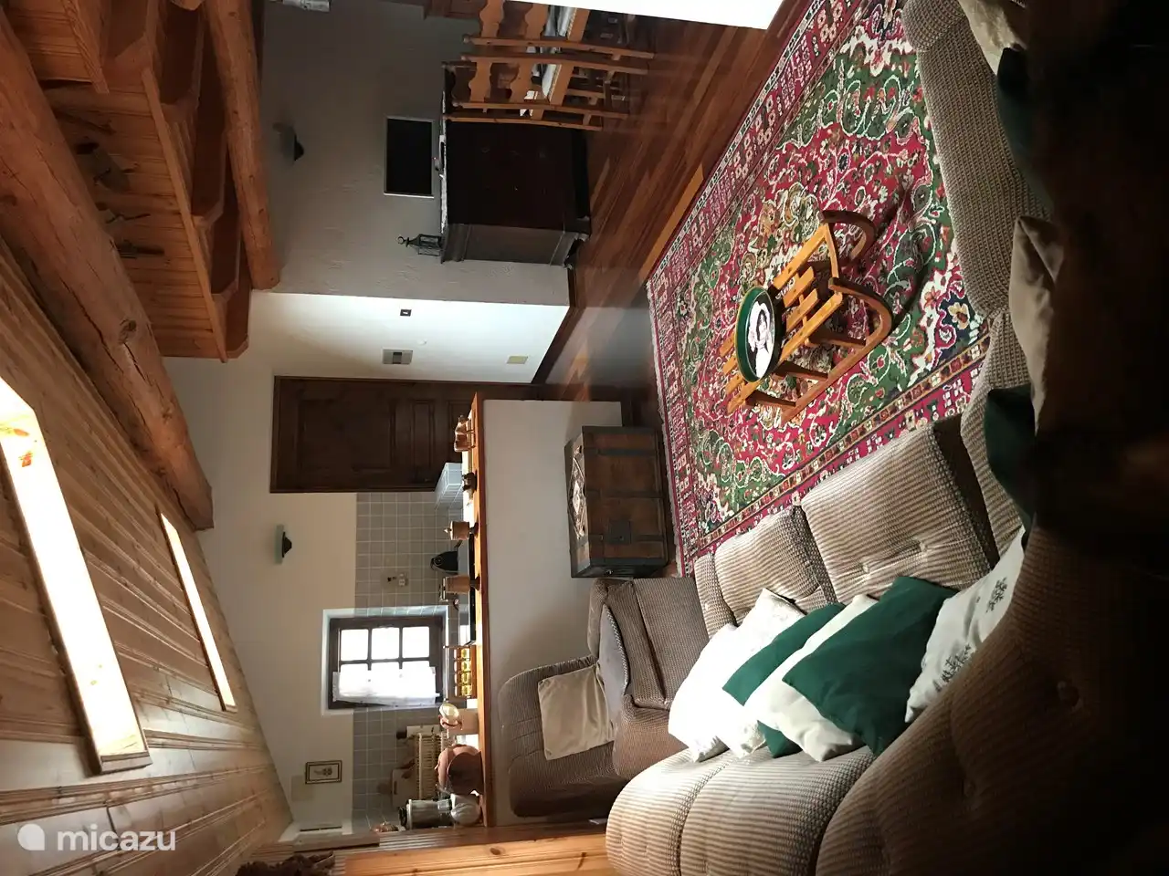 Das Wohnzimmer mit Küchenzeile und Essbereich. Die Materialien sind weich und samtig: Woll- oder Flanelllaken für das Sofa und die Kissen, Wolle für die Teppiche.