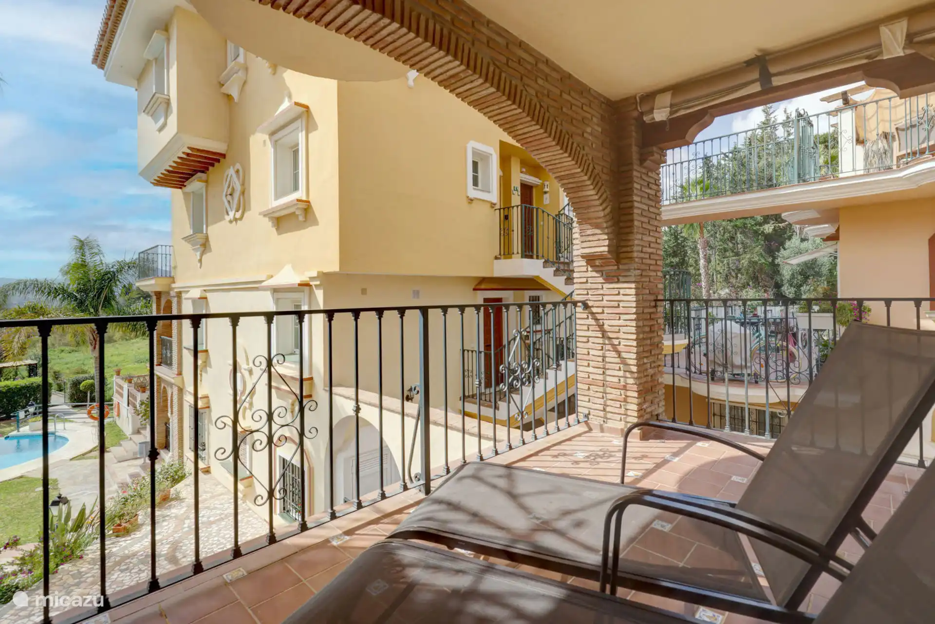 Terras met ligstoelen met uitzicht op het zwembad en de tuinen