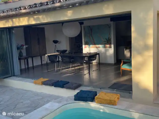 La Petite Villa Amarilla en Francia, Costa Azul, Grimaud - casa vacacional Vista desde la piscina hacia el comedor con cojines para sentarse adicionales