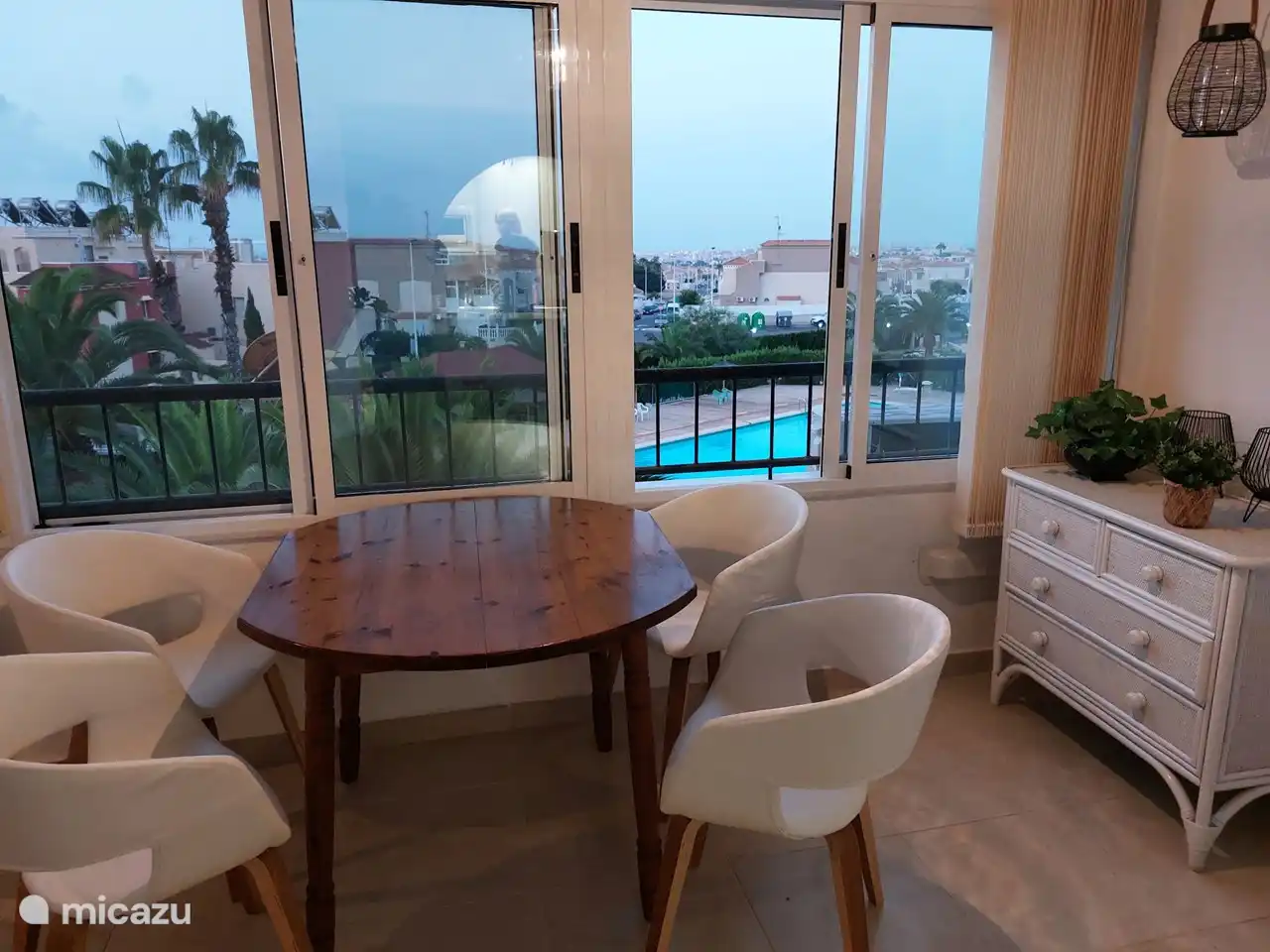 The dining table on the balcony overlooking the sea, city and pool