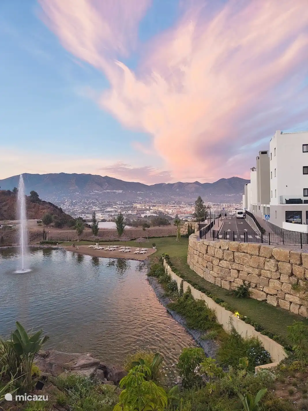 Lagune mit Brunnen und Strand mit Sonnenbetten.