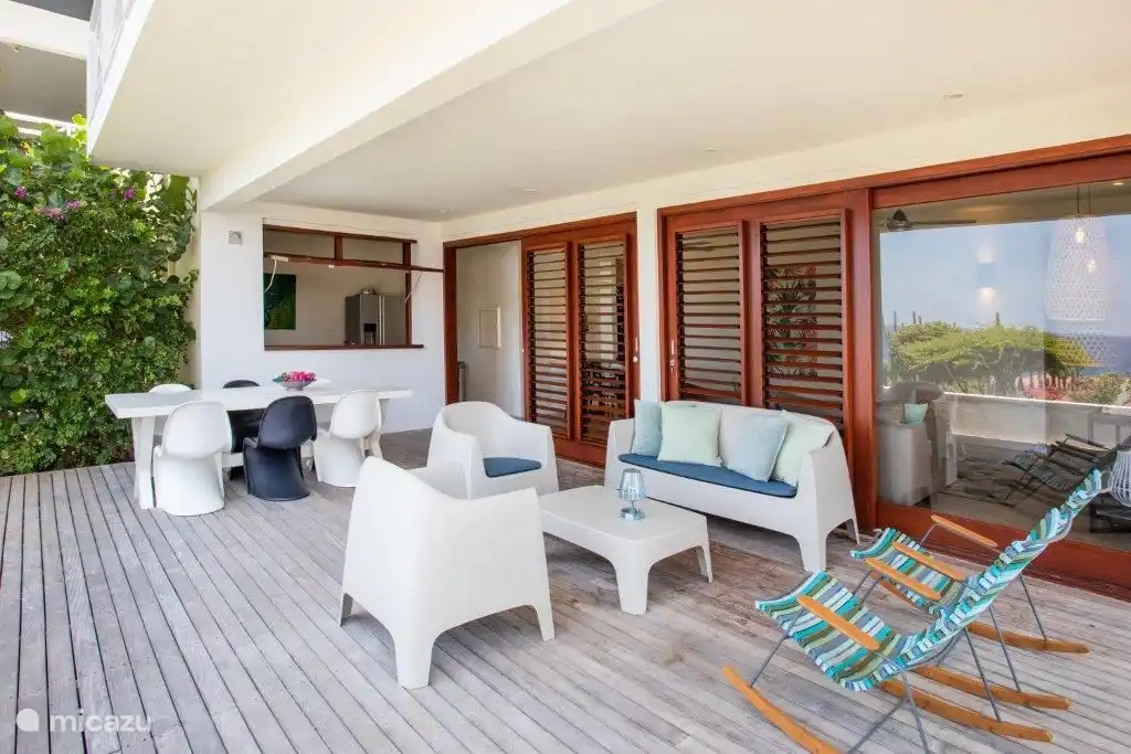 Mobilier d'extérieur confortable pour une assise agréable à l'ombre et passe-plat vers la cuisine.