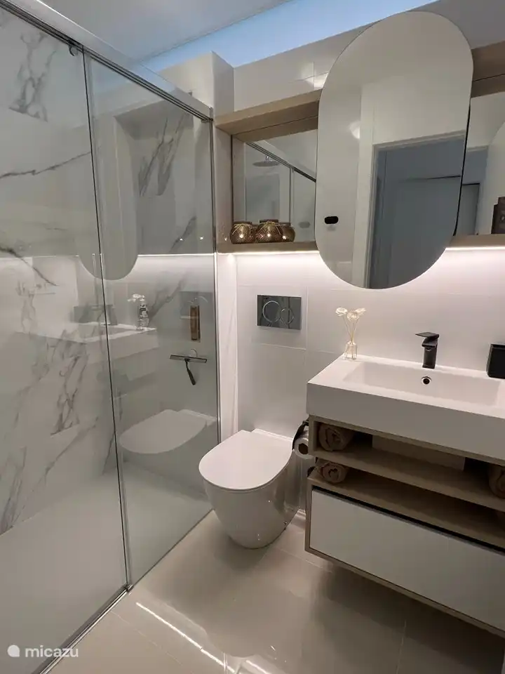 Badezimmer 2 mit Regendusche, Toilette, Waschbecken, Abstellschrank und Fußbodenheizung.