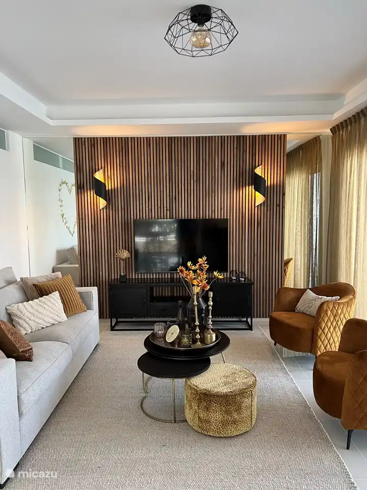 Wohnzimmer mit 2,5-Sitzer-Sofa, 2 Sesseln, Spielen im Fernsehschrank, Fernseher und attraktiver Dekoration.