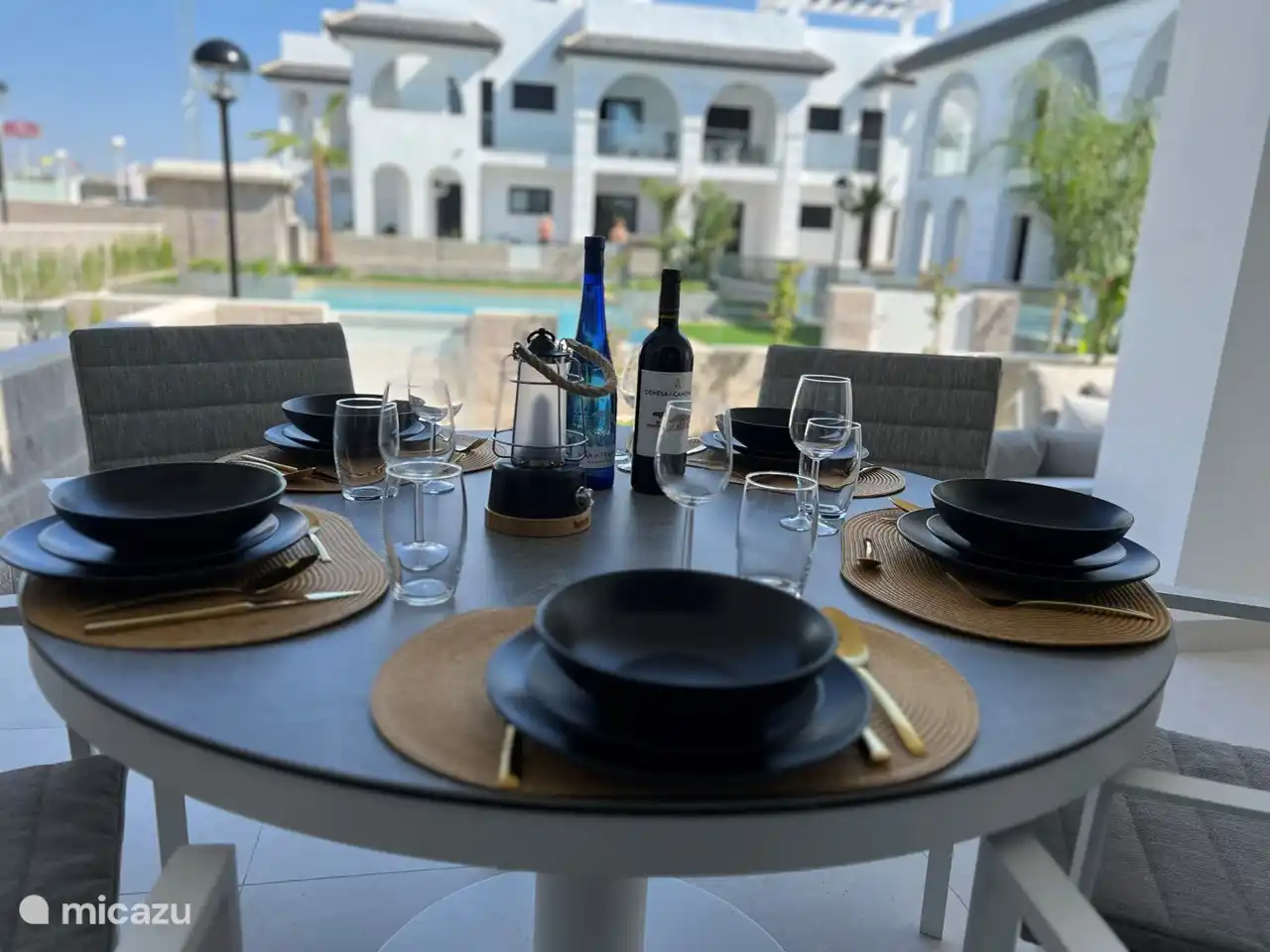 Esstisch im Freien auf der überdachten Terrasse mit 5 Esszimmerstühlen inklusive Kissen und Blick auf den Swimmingpool.
