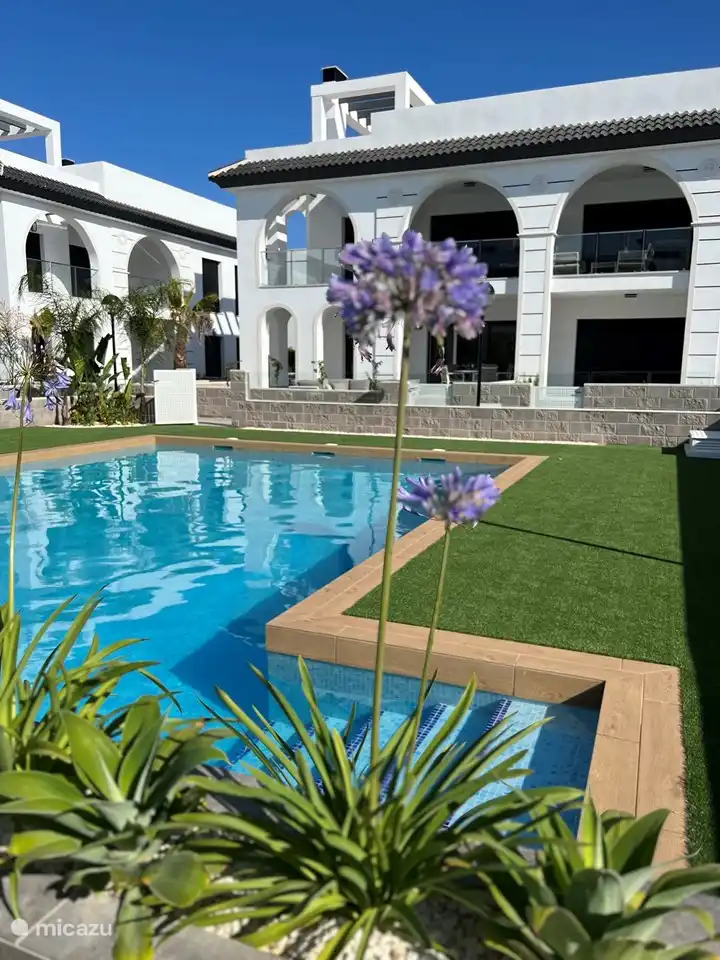 Sonniges Schwimmbad mit Sonnenliegen und Sonnenschirmen. Separates Kinderbecken.