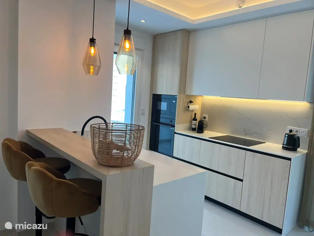 Offene Küche mit Backofen, Mikrowelle, Geschirrspüler, Kühlschrank, großem Gefrierschrank, Induktionskochfeld, Wasserkocher, Nespresso-Kaffeemaschine und Safe.