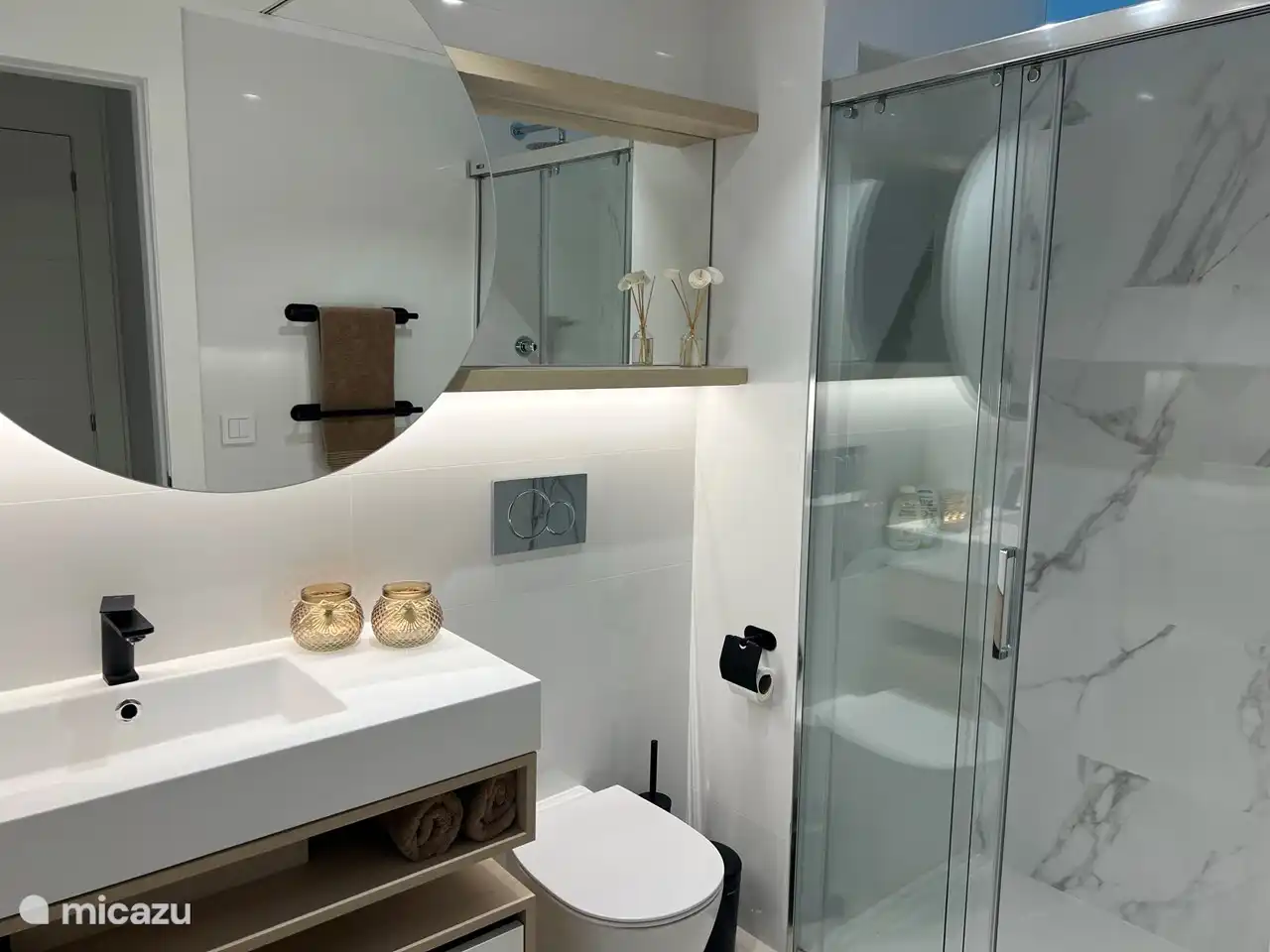 Badezimmer 1 mit Regendusche, WC, Waschbecken, Abstellschrank, Haartrockner und Fußbodenheizung.