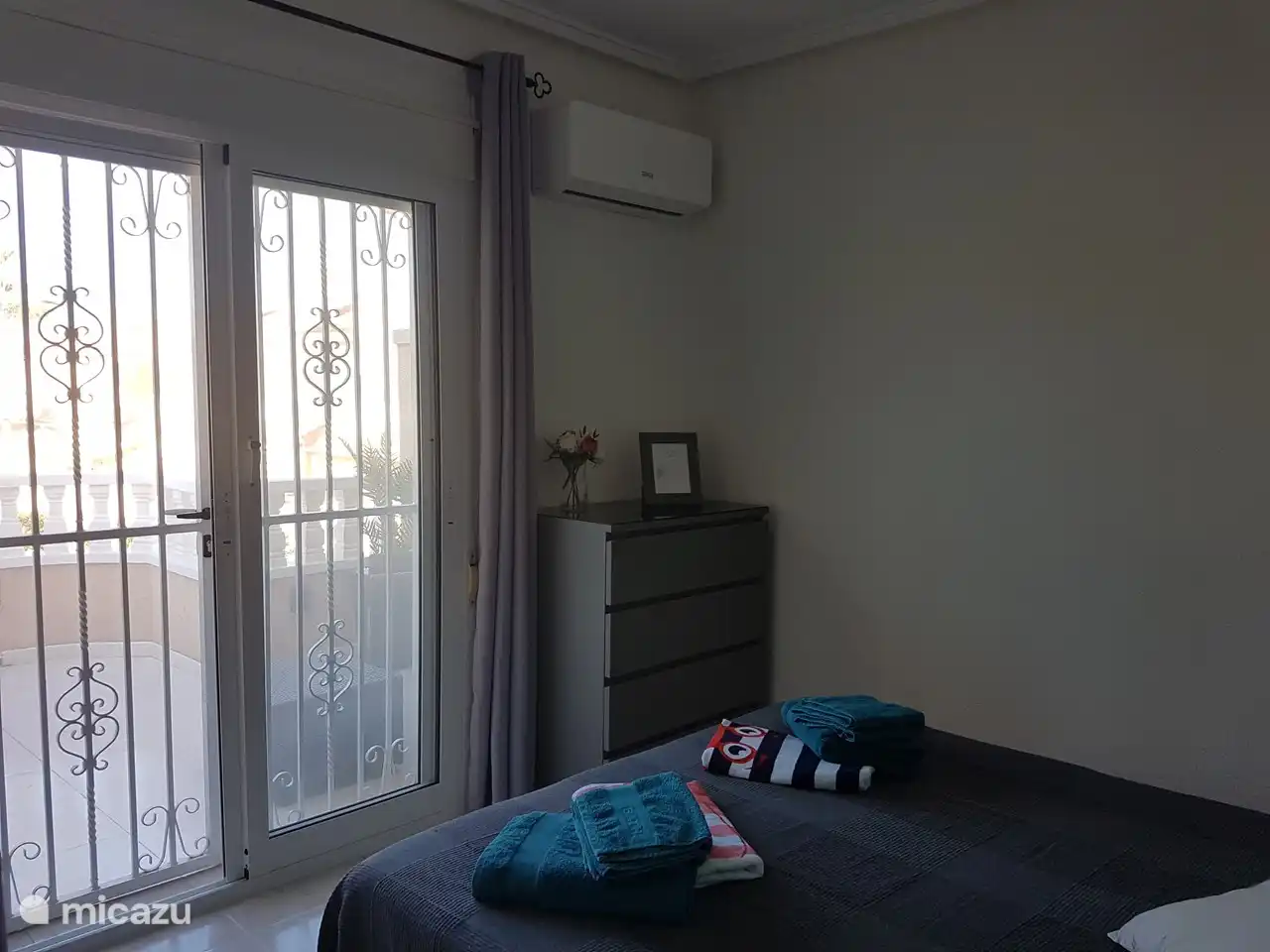 Hauptschlafzimmer mit Zugang zum Balkon und Blick auf den Pool