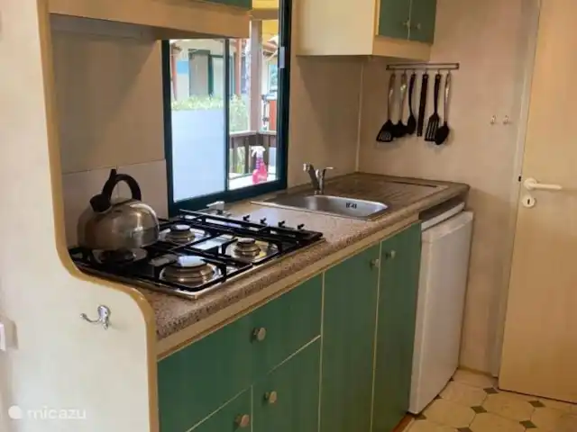 Chalet Fam VI - avec véranda et climatisation ! | Italie, Toscane, Viareggio - mobil-home La cuisine ouverte dispose d'une plaque de cuisson à gaz 4 feux, d'un réfrigérateur avec congélateur et d'un vaste inventaire.