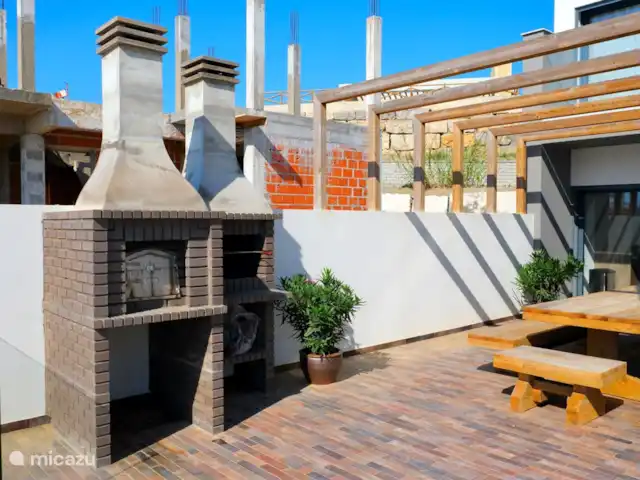 villa en Portugal, Costa de Lisboa, Ribamar – Sapateira Terraza adyacente al lado oeste de la casa. Se puede llegar a esta terraza a través de las puertas correderas de la cocina. Esta terraza tiene un horno de barbacoa/pizza. Es maravilloso cenar en la gran mesa normal.