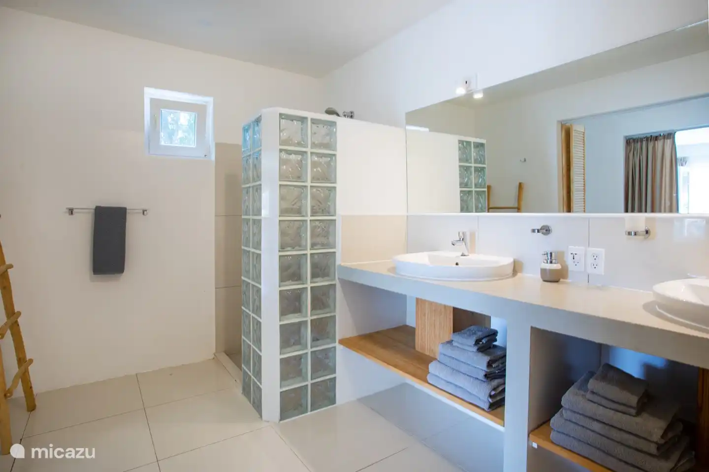 Das Badezimmer verfügt über ein Doppelwaschbecken, eine Dusche und eine Toilette