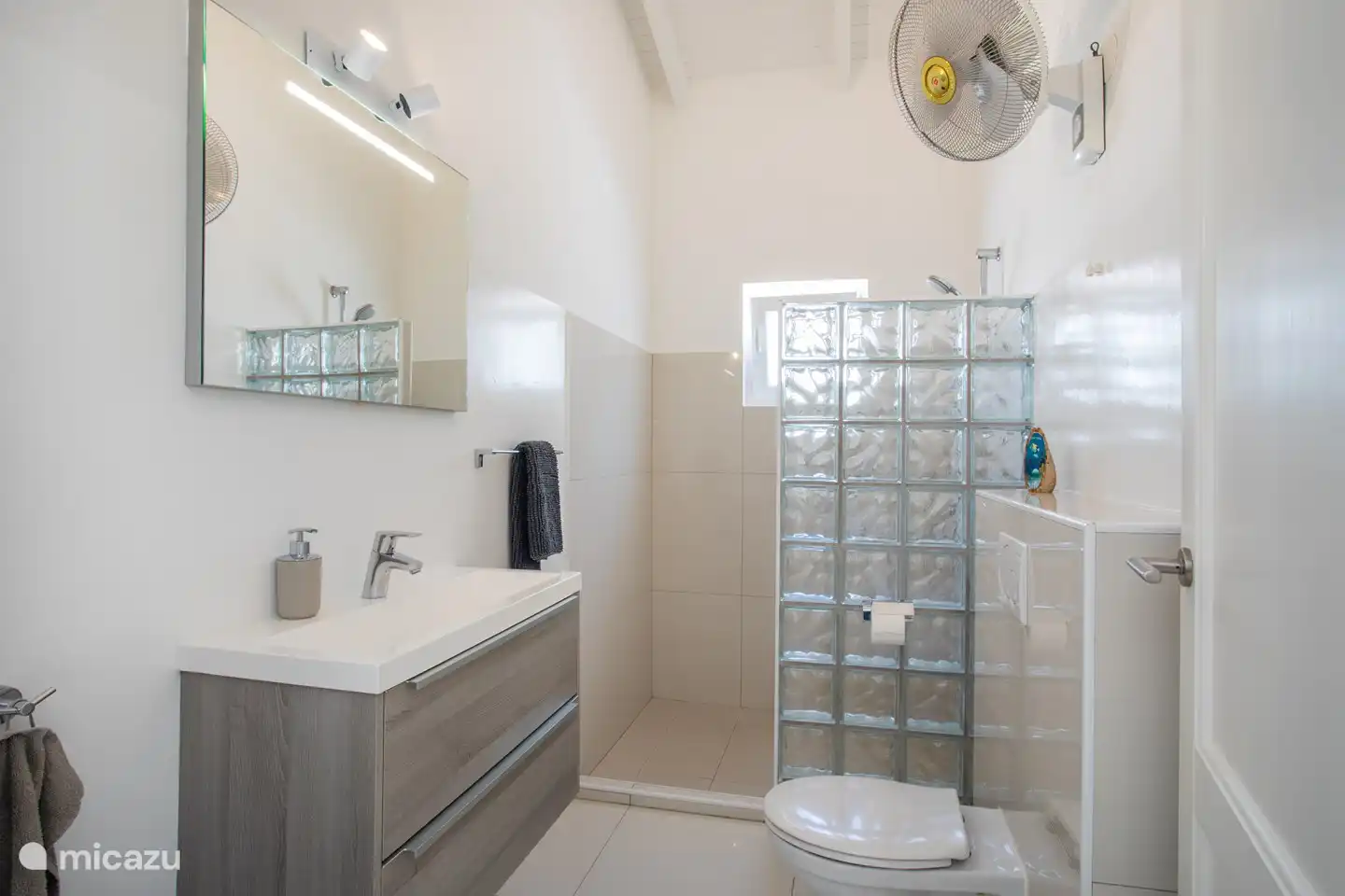 Das Badezimmer in der Wohnung ist geräumig und verfügt über ein Waschbecken, eine Dusche, eine Toilette und einen Ventilator.