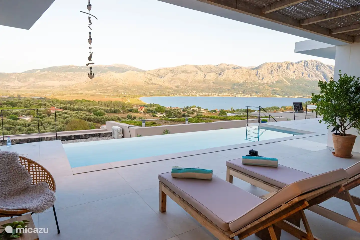 Vue sur la piscine, la baie de Paleros (Pogonia) et les montagnes depuis la table à manger sous la terrasse couverte