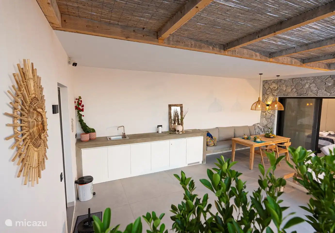 Terrasse couverte entre le bâtiment principal et les chambres avec table à manger, rangements dans les placards et réfrigérateur extérieur et évier avec eau froide et chaude