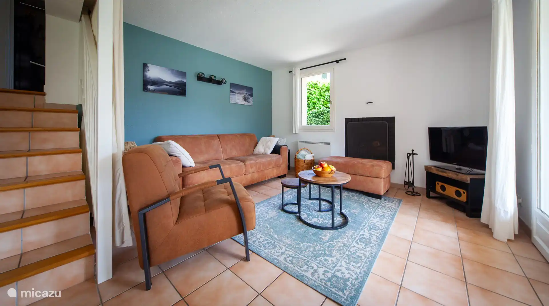 Von der Loggia aus gelangen Sie durch französische Türen in das Wohnzimmer mit einer großzügigen Sitzecke mit Kamin. Außerdem gibt es einen Fernseher, Bluetooth-Lautsprecher und WLAN.