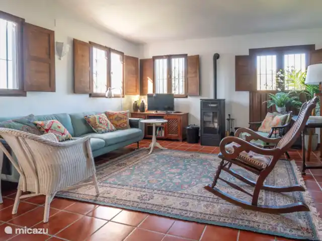 vakantiehuis huren in Spanje, Andalusië, Cómpeta – Finca Galliano Woonkamer met veel ramen. Op de achtergrond de pelletkachel voor snelle probleemloze verwarming in de koudere maanden.