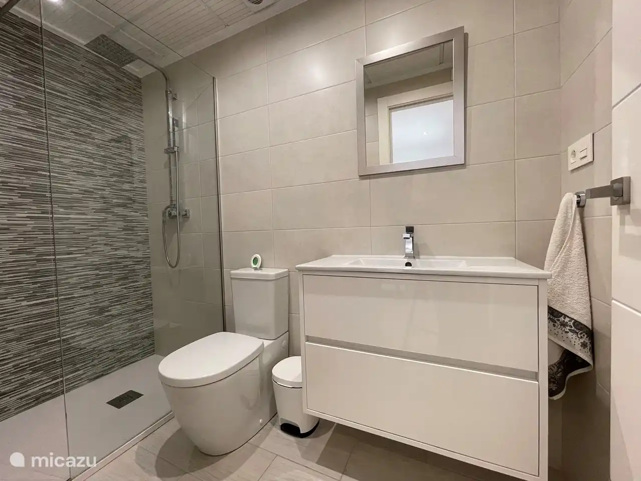 Salle de bain soignée avec douche à l’italienne, lavabo et toilettes.