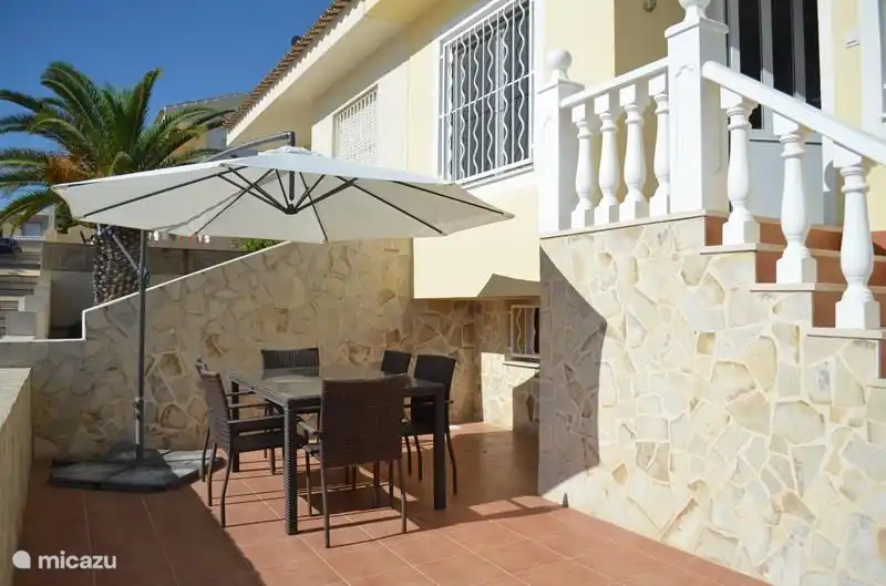 Mesa de comedor con sombrilla en la parte delantera de la casa.